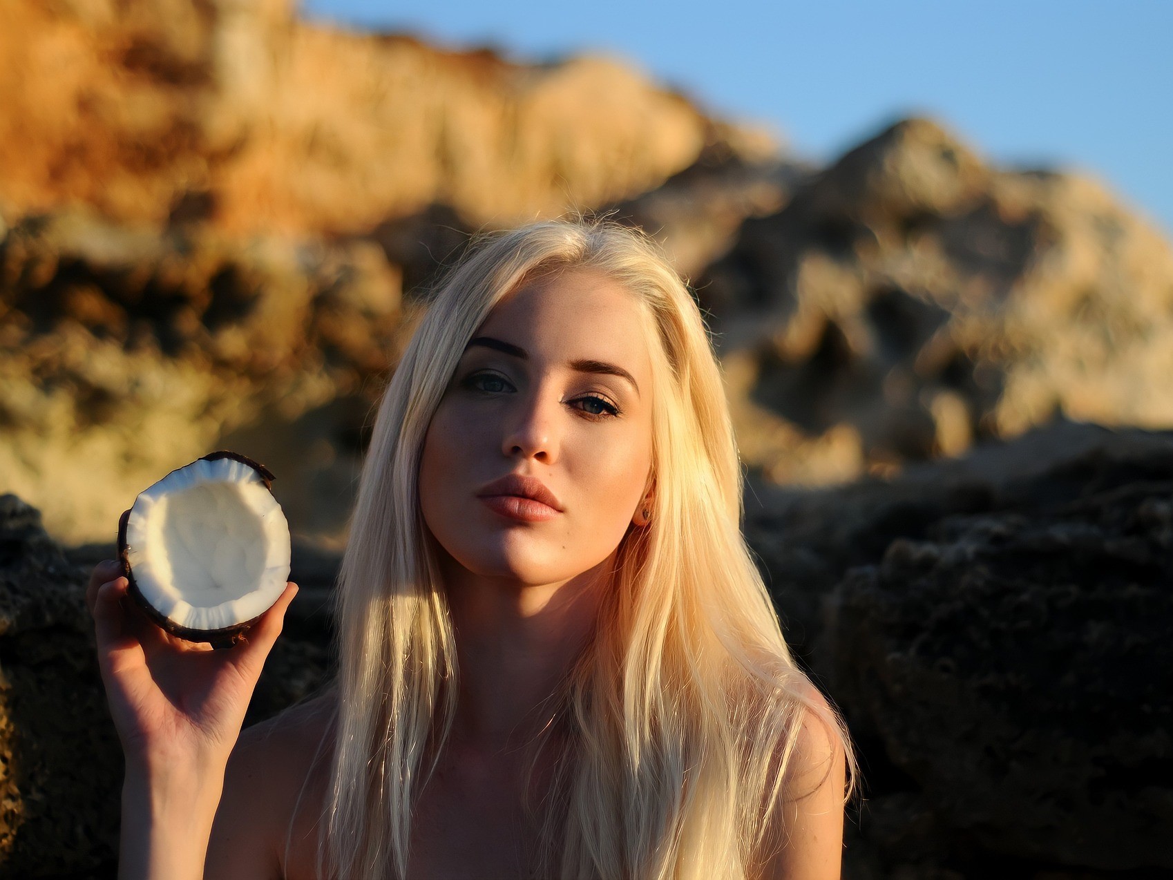 Blondine mit halber Kokosnuss in der Hand