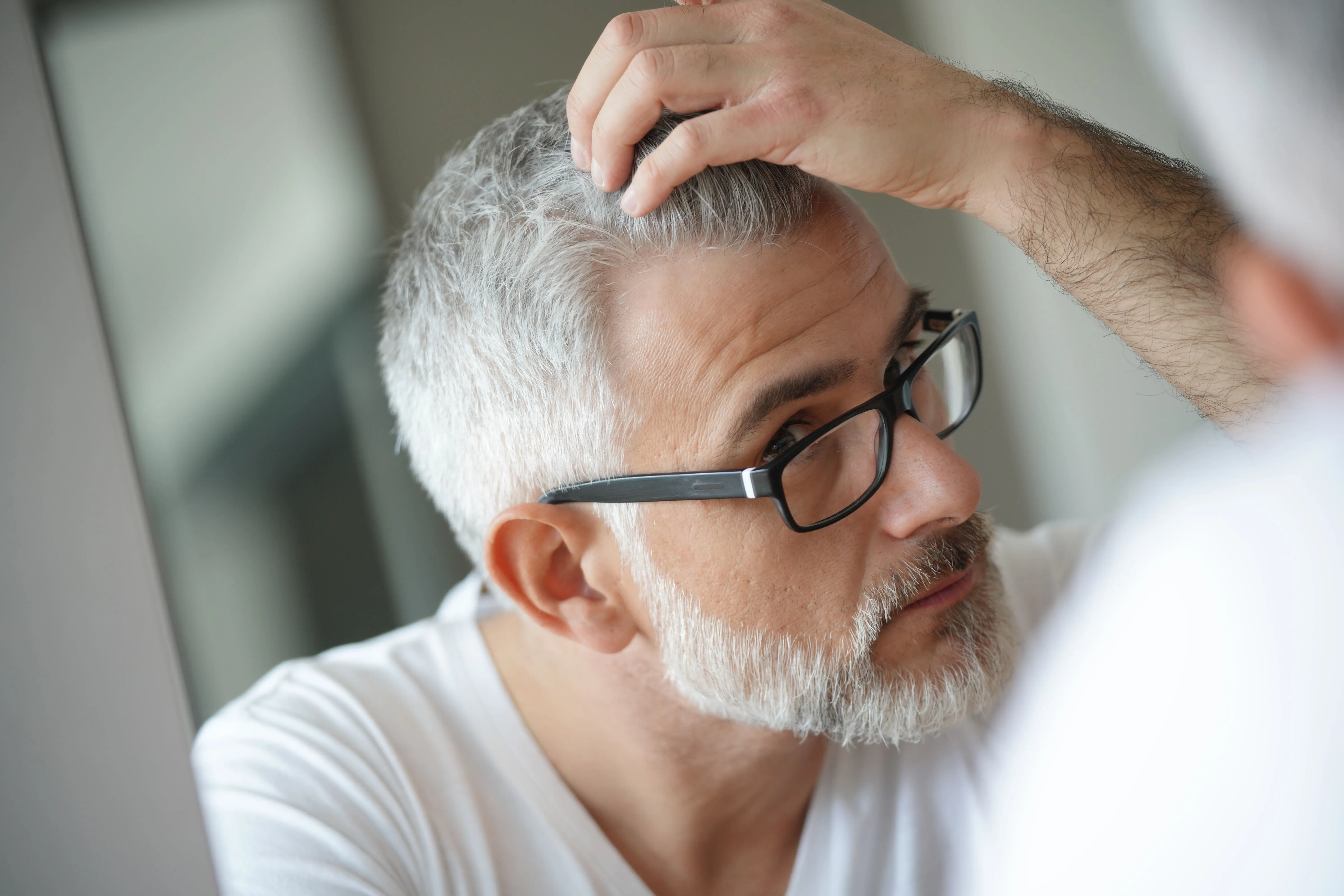 Mann mit Brille betrachtet seine Haare