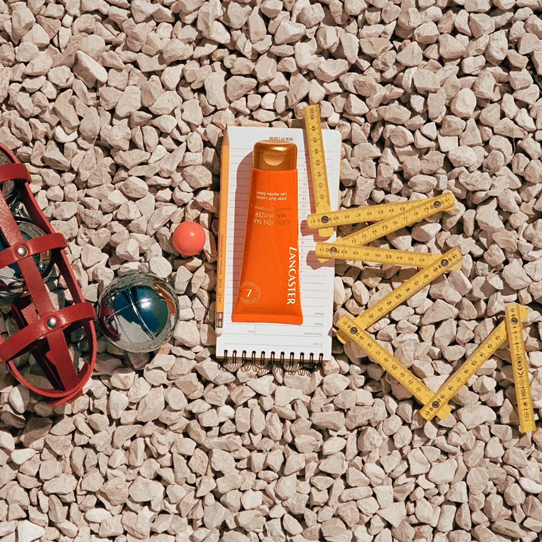 Lancaster Sonnenschutzcreme liegt am Kiesstrand