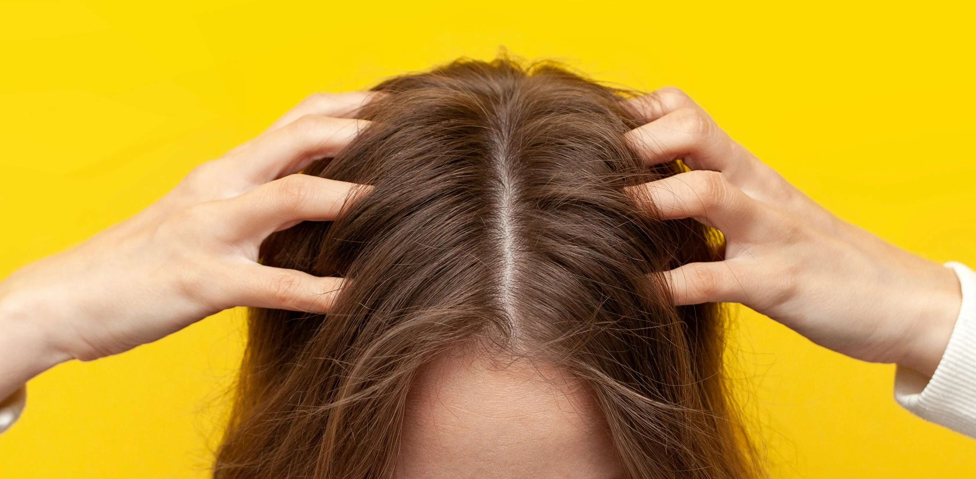 Frau greift sich auf die Kopfhaut