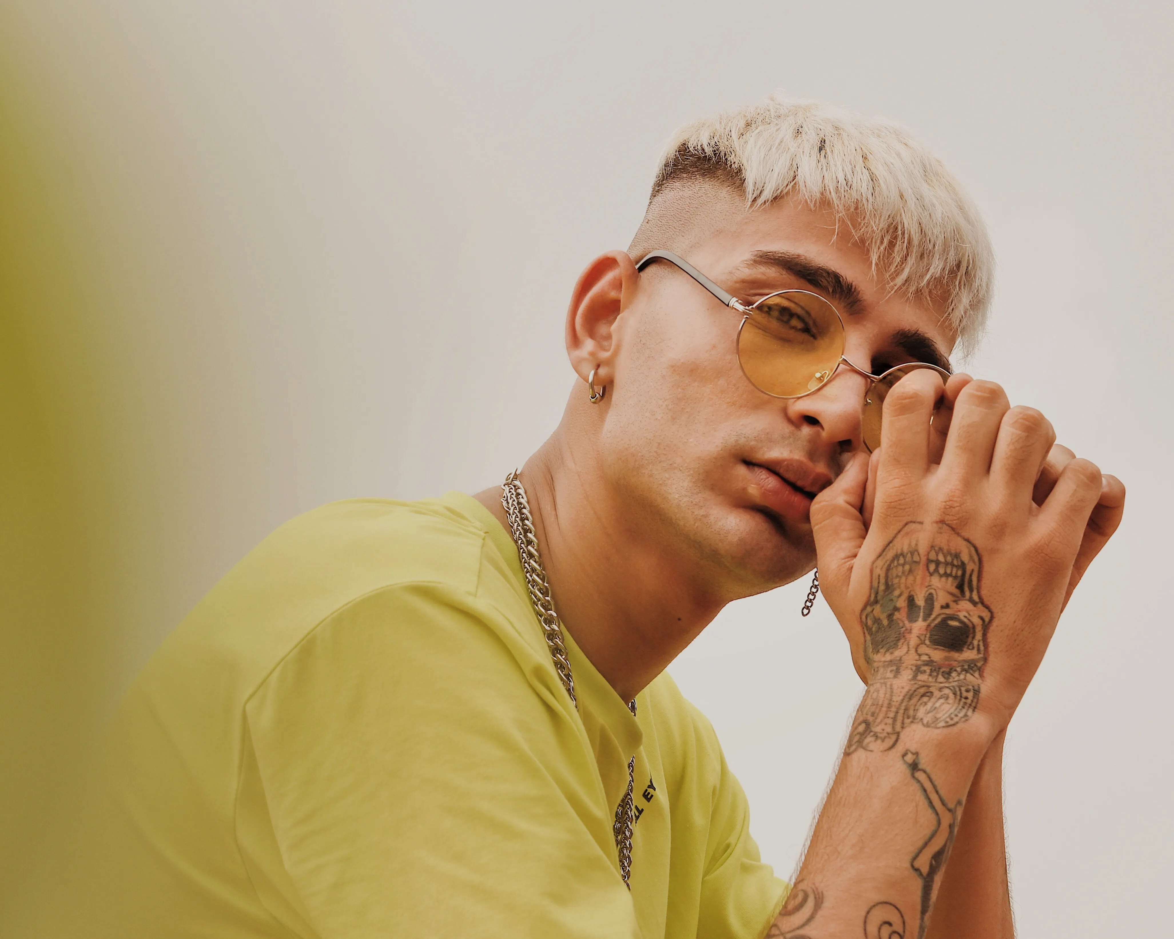Blonder Mann mit Brille und Tattoo auf der Hand